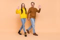 Full body photo of brunette funny couple hold arms go wave wear sweaters jeans boots isolated on beige background