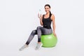 Full body photo of brunette ponytail haired young lady sit fitball hold bottle water on grey color background