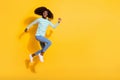 Full body photo of carefree excited girl running jumping empty space ad isolated on yellow color background