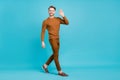 Full body photo charming happy young man walk go empty space wave hello isolated on blue color background