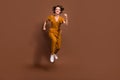 Full body photo of charming joyful young woman jump up run hurry sale discount isolated on brown color background