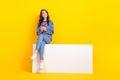 Full body photo of cheerful nice lady sit empty space banner hold telephone isolated on yellow color background
