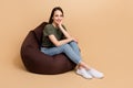 Full body photo of cheery lady relaxed touch cheek sitting beanbag waiting cocktails at lounge zone isolated on beige Royalty Free Stock Photo