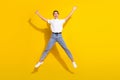 Full body photo of cool brown hairdo young lady jump wear white t-shirt jeans isolated on yellow color background Royalty Free Stock Photo