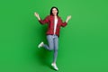 Full body photo of crazy brunette hairdo young lady jump wear red shirt jeans isolated on green color background