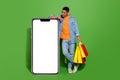 Full body photo curious young man go shopping using huge smartphone to shop online isolated on green color background