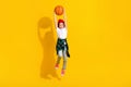 Full body photo of cute small girl raise catch basketball ball dressed stylish white clothes isolated on yellow color