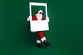 Full body photo of elderly retired man hold instant photo frame wear trendy santa claus costume coat isolated on green