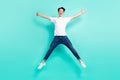 Full body photo of funky brunet hairdo teen guy jump wear t-shirt jeans isolated on teal background