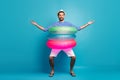 Full body photo of handsome guy traveler get inside three colorful rubber lifebuoys going to swim pool sea ocean wear