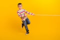 Full body photo of kid boy have weekend free time play active sport game tug war isolated on bright color background Royalty Free Stock Photo