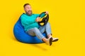 Full body photo of nice grandpa beanbag play car simulator steering wheel wear trendy aquamarine look isolated on yellow Royalty Free Stock Photo