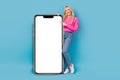 Full body photo of optimistic girl promoter direct finger empty space phone display recommend game store  on Royalty Free Stock Photo