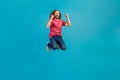 Full body photo of overjoyed energetic person raise fists jumping empty space isolated on blue color background