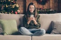 Full body photo of positive festive girl sit on divan crossing her legs using cellphone communicating enjoy christmas Royalty Free Stock Photo