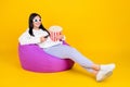 Full body photo of positive lady sit bean chair watch comedy hold pop corn basket isolated over bright yellow color