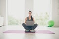 Full body photo of positive sportive girl crossing her legs sit on violet mat use laptop browse films movie about sport Royalty Free Stock Photo