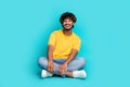 Full body photo of positive young man sitting floor crossed legs good mood isolated on teal color background Royalty Free Stock Photo