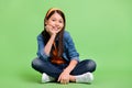 Full body photo of pretty preteen girl sit wear shirt jeans hairband footwear isolated on green background Royalty Free Stock Photo