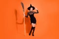 Full body photo of pretty young girl touch hat hold broom dressed trendy black halloween witch clothes isolated on Royalty Free Stock Photo