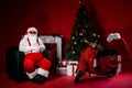 Full body photo of santa claus sit in chair fairy house concept with fir tree motorcycle x-mas ornament isolated shine