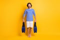 Full body photo of surprised guy hold snorkeling fins wear blue white frock shorts isolated on bright yellow color Royalty Free Stock Photo