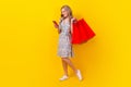 Full body photo of young blonde wavy hair girl hold bags shoppers clothing read phone virtual store isolated on yellow