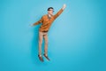 Full body photo of young excited man try catch umbrella jump up look empty space isolated over blue color background Royalty Free Stock Photo