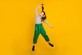 Full body photo of young excited school girl jump up hold ponytail funky over yellow color background