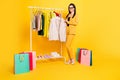 Full body photo of young woman happy smile choose new clothes store customer bags shopping isolated over yellow color