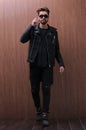 A man is standing in a black leather jacket and jeans Royalty Free Stock Photo