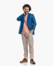 happy casual young man with curly hair with hand in pocket touching neck Royalty Free Stock Photo