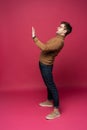 Full body picture of a young casual man presenting something on pink background. Royalty Free Stock Photo