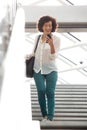 Full body african american woman walking down stairs with cellphone Royalty Free Stock Photo