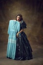 Full body portrait of attractive young woman wearing, black balldress made of garbage bags holding blue midi dress and Royalty Free Stock Photo
