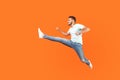 Full body portrait of excited brunette man jumping over in air, running quickly fast. isolated on orange background