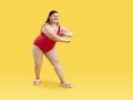 Funny young fat woman in red swimsuit having fun isolated on studio yellow background Royalty Free Stock Photo