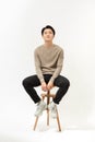Full body portrait of handsome young Southeast Asian man sitting on high chair