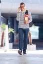 Happy male college student walking on campus with book bag and mobile phone Royalty Free Stock Photo