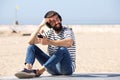 Happy man in headphones sitting on beach with smile Royalty Free Stock Photo