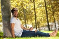 Happy man sitting in grass with cellphone and headphones Royalty Free Stock Photo