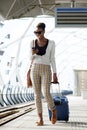 Full body happy travel woman walking with suitcase and cellphone at train station Royalty Free Stock Photo