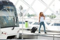 Full body happy woman walking at train station with mobile phone and bag Royalty Free Stock Photo