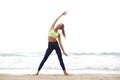 Full body happy yoga woman stretching at the beach