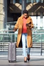 Full body happy young african american woman walking in station with suitcase and mobile phone Royalty Free Stock Photo