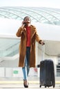 Full body happy young african american woman walking with suitcase luggage and cellphone Royalty Free Stock Photo