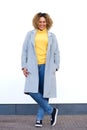 Full body happy young african american woman in winter coat standing against white wall Royalty Free Stock Photo