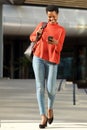 Full body happy young african woman walking with cellphone outside in city Royalty Free Stock Photo