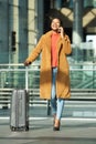 Full body happy young black woman walking in station with suitcase and mobile phone Royalty Free Stock Photo