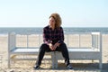 Happy young woman sitting on bench at the beach Royalty Free Stock Photo